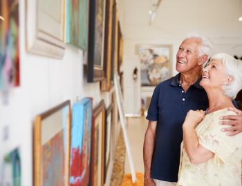 A man and woman viewing art pieces hanging on a wall in a gallery