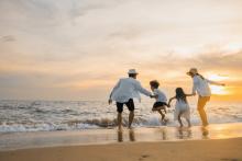 A family of four holding hands on a beach at sunset