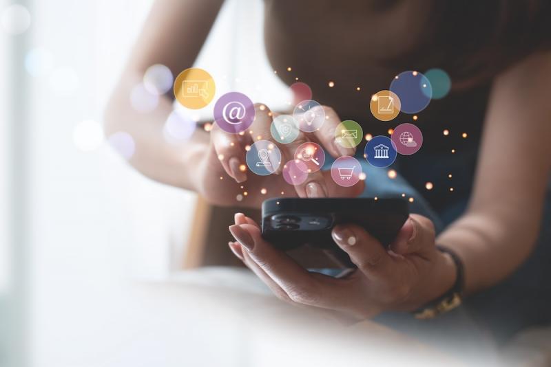 woman holding phone with colorful bubbles of icons hovering over it