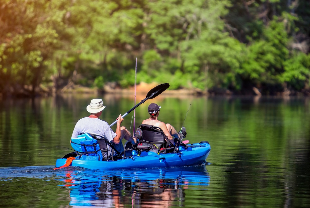 Two people kayaking in a body of water surrounded by trees