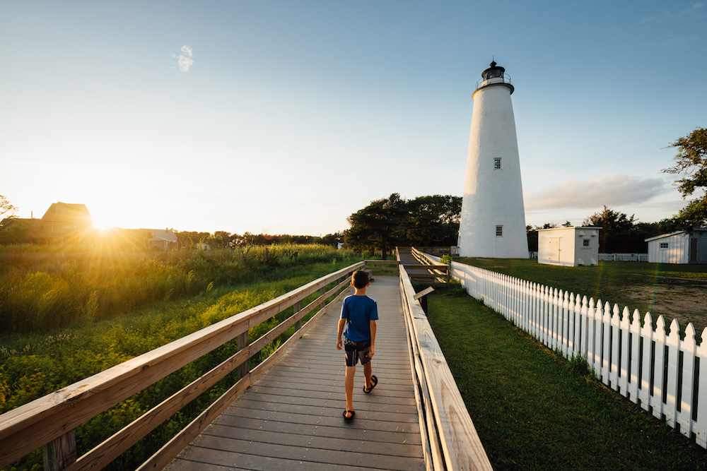 child walking on boardwalk toward a lighthouse in the Outer Banks