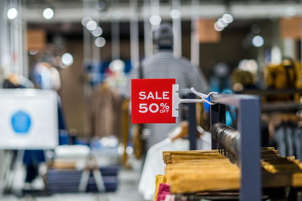 An outlet store clothing rack with a "50% off" sign